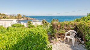 Una proprietà costiera con vista sul mare, una sedia bianca e vegetazione lussureggiante.
