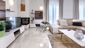 Ein modernes Wohnzimmer mit Flachbildfernseher, Kamin, Sofa und Couchtisch.