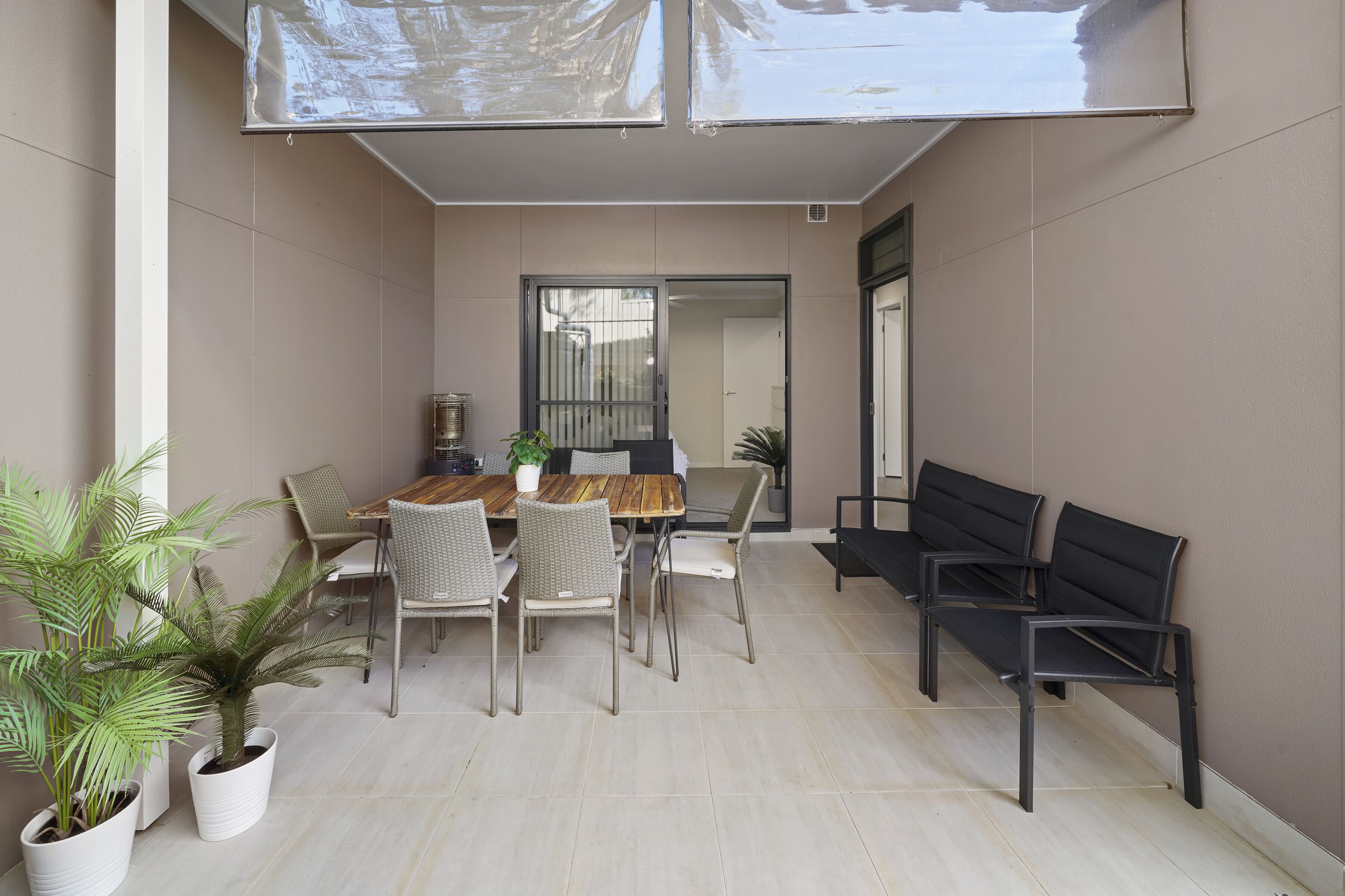 A dining area with a wooden table, white chairs, and potted plants.