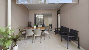 A dining area with a wooden table, white chairs, and potted plants.