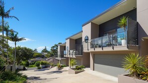 A modern residential building with a spacious driveway, multiple balconies, and well-maintained landscaping. - Spacious 4BR w/ Water Views (Port Macquarie)