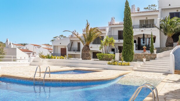 A swimming pool with metal railings, surrounded by white buildings with balconies and palm trees. - WELCS CASA ADOSADA 215 EMP con piscina comunitaria (Rosas / Roses)