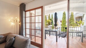 A modern living room with a sofa, a glass door leading to an outdoor patio with a table and chairs. - WELCS CASA ADOSADA 215 EMP con piscina comunitaria (Rosas / Roses)