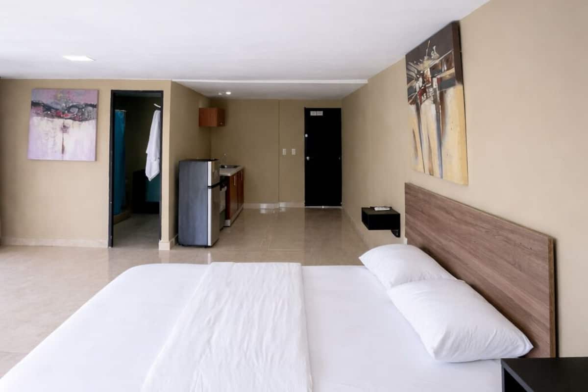 A spacious hotel room with a large bed, a desk, and a view of the hallway.