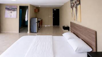 Amplia habitación de hotel con una cama grande, un escritorio y vista al pasillo.