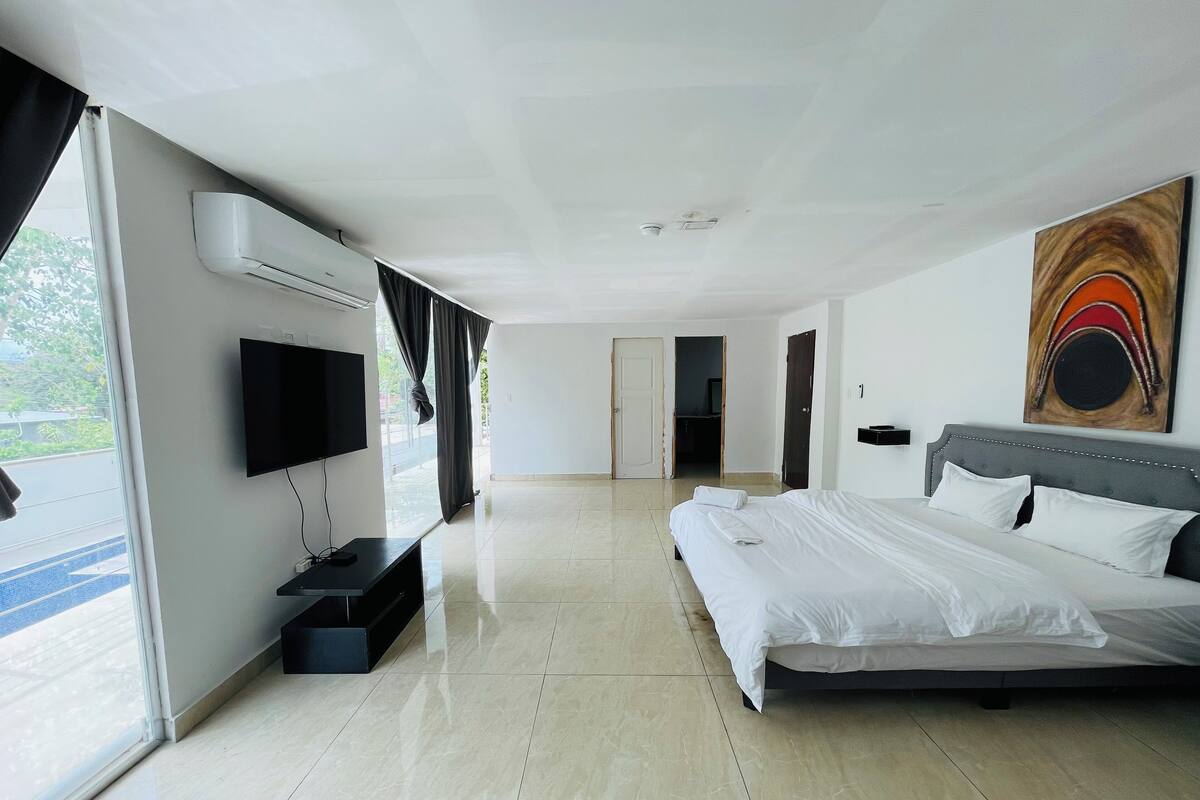 A modern hotel room with a large bed, a flat-screen TV, and a painting on the wall.