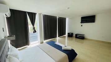 Une chambre d’hôtel équipée d’un lit, d’un téléviseur à écran plat, d’un ventilateur de plafond et d’une fenêtre avec des rideaux.