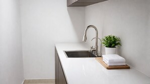A modern kitchen with a sink, a potted plant, and a wooden cutting board.