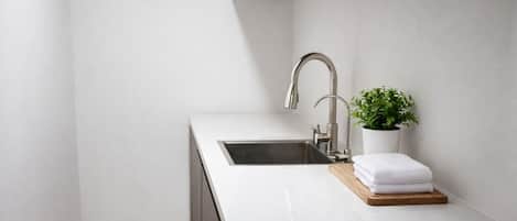 Cocina moderna con un lavamanos, una planta en maceta y una tabla de cortar de madera.