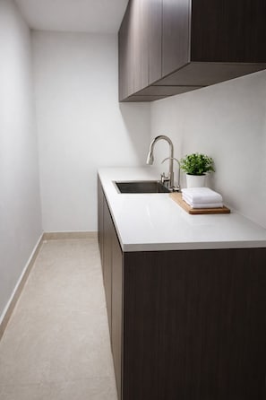 A modern kitchen with a sink, a potted plant, and a wooden cutting board. - Gorgona Beach Hotel (Nueva Gorgona)