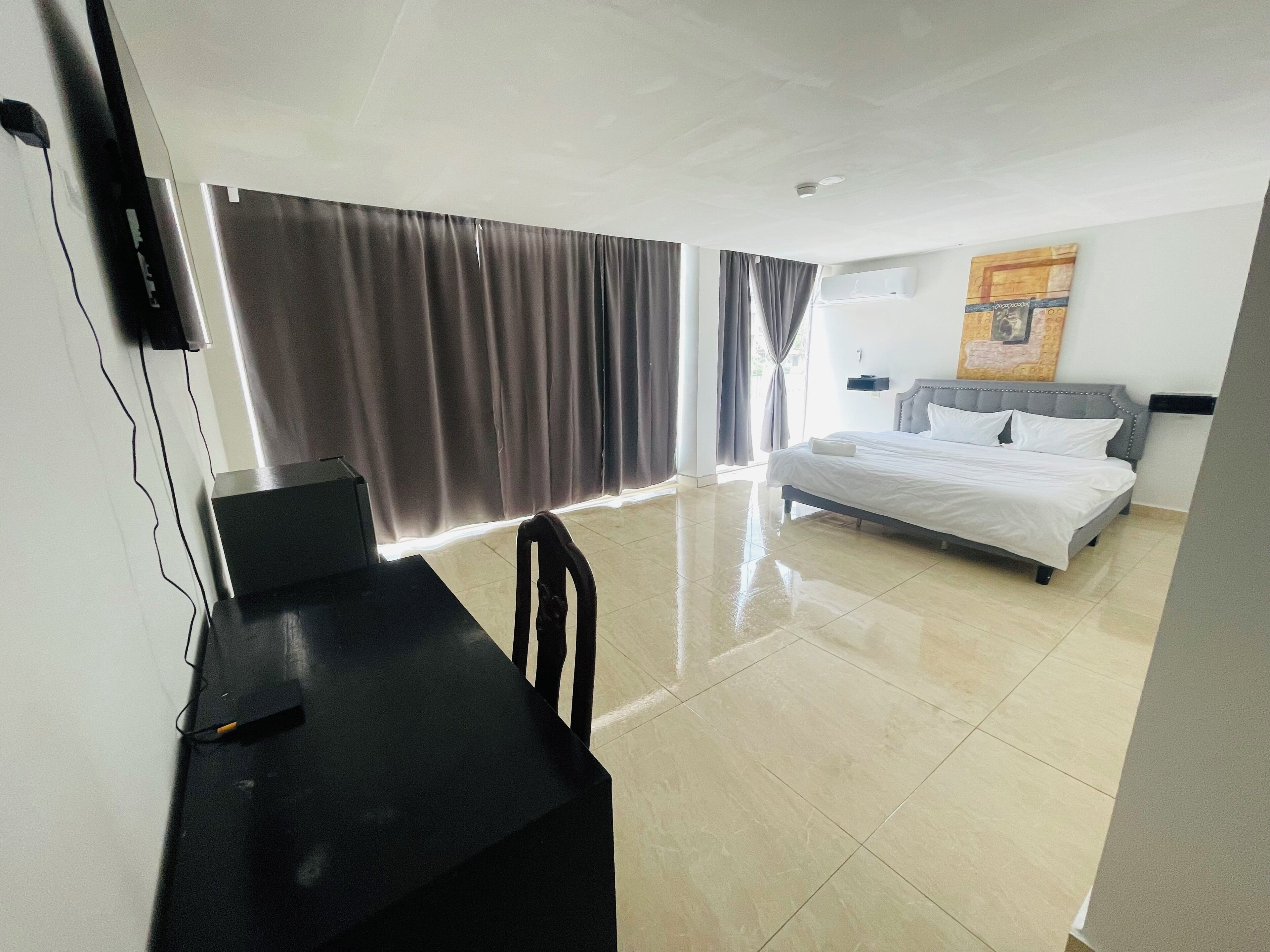 A hotel room with a bed, a desk, a chair, and a TV.