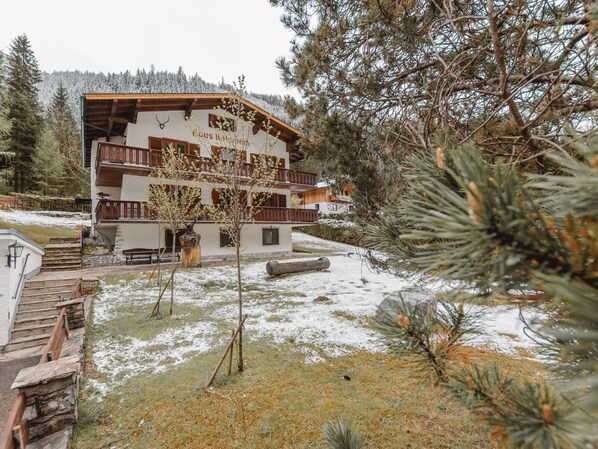 A multi-story building with wooden balconies, surrounded by snow-covered ground and pine trees.