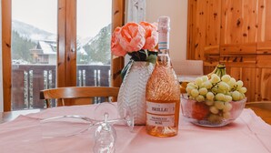 A table with a bottle of Brilla! Prosecco Rosé, a glass vase with flowers, and a bowl of grapes. - Haus Kötschach by Interhome (Bad Gastein)