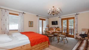 A cozy room with a bed, a wooden desk with a chair, a television, and a sofa. - Haus Kötschach by Interhome (Bad Gastein)