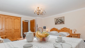 Un dormitorio ordenado con cama, mesita de noche y una zona de comedor con una mesa dispuesta para dos personas.