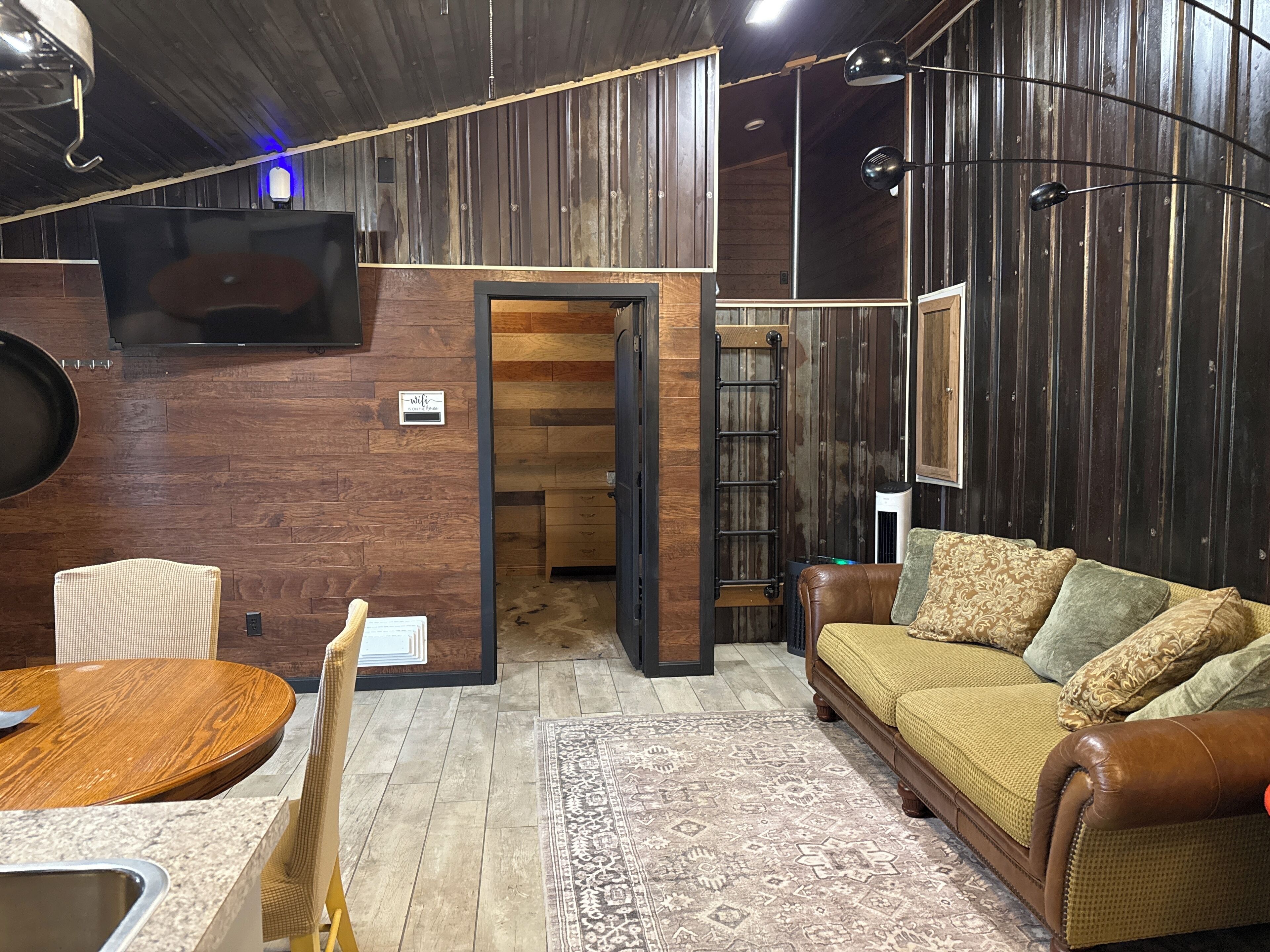 Un salon chaleureux avec un canapé en cuir marron, une table ronde en bois et un tapis à motifs.