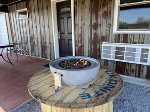 A fire pit on a wooden table outside a building with a metal door and a window. - The Rustic Suite on Bourbon Trail (Loretto)