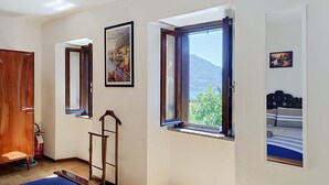 Une pièce avec un lit, une fenêtre donnant sur une montagne, une porte et une échelle.