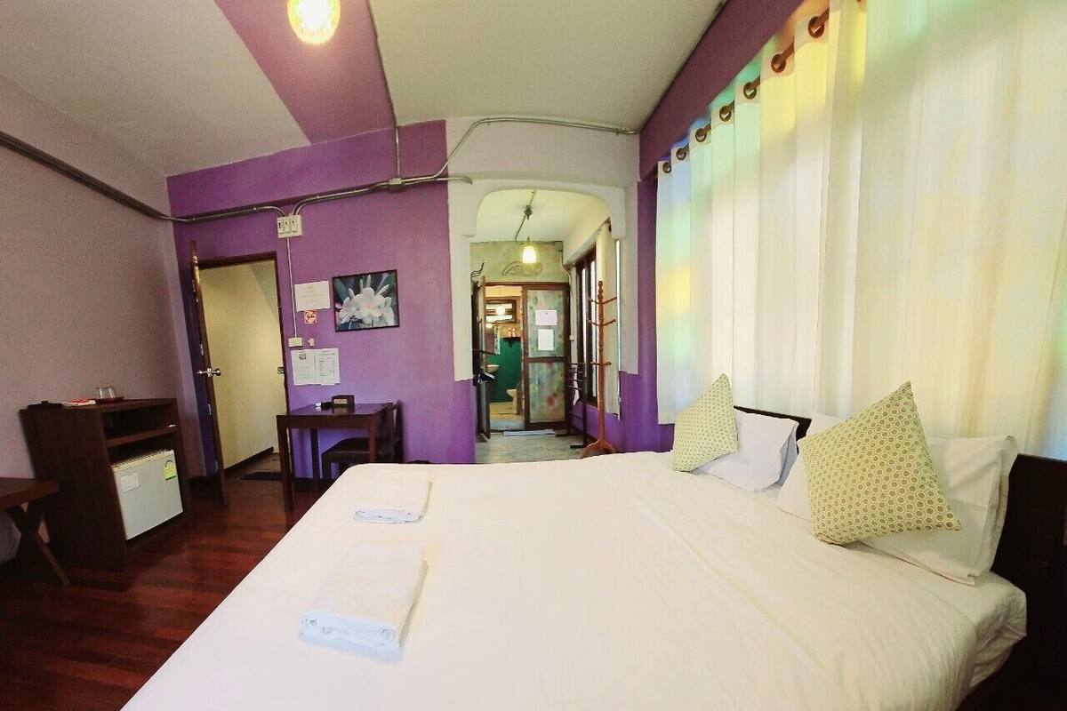 A hotel room with a large bed, a desk, and a chair.