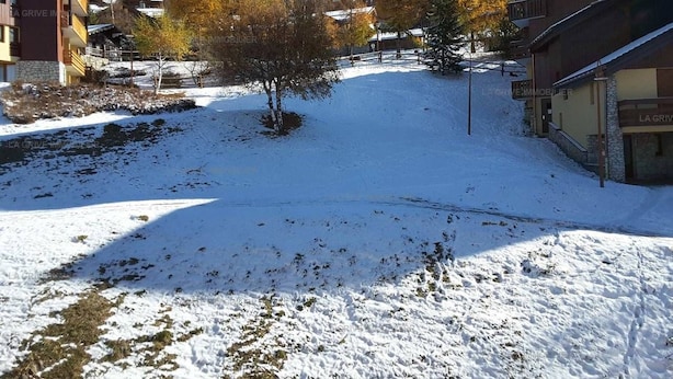 Un espacio al aire libre cubierto de nieve, con edificios y árboles.