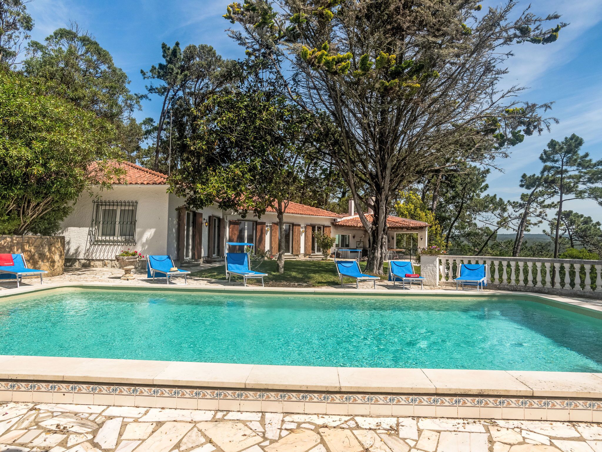 Ein Poolbereich mit blauen Liegestühlen und einer Poolumrandung aus Fliesen.