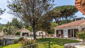 Eine Villa mit Swimmingpool, einem gepflasterten Weg und einem gepflegten Garten.