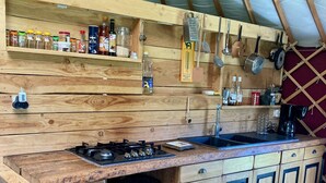 Eine rustikale Küche mit Holzschränken, einem Gasherd und diversen Küchenutensilien.