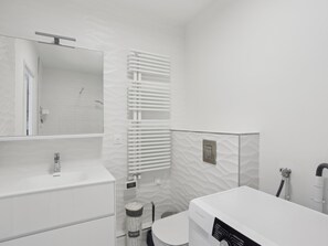 Bathroom features a white vanity, toilet, and shower area with a towel rack.