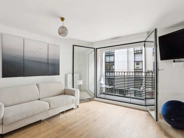 Relax in this stylish living room with a sofa, abstract art, and a balcony with a metal railing.