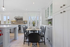 Una cocina moderna con armarios blancos, una isla central y un comedor con sillas negras.