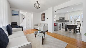 Ein modernes Wohnzimmer mit Sofa, Couchtisch und einem Essbereich mit Stühlen und Tisch.