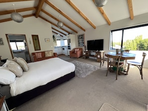 A spacious room with a large bed, a dining table, and a kitchen area. - Cosy, comfortable Loft with free wi-fi set in a great location of the West Coast (Greymouth)