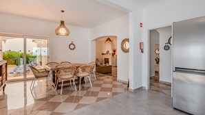 Een moderne keuken met een roestvrijstalen koelkast, zwarte en witte vloertegels en rieten stoelen rond een eettafel.