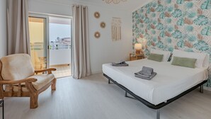 Een slaapkamer met een bed, een stoel, een nachtkastje en uitzicht.