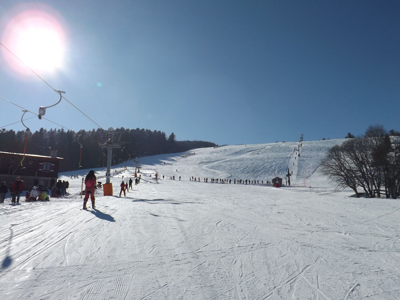 Een skipiste met skiliften, een klein gebouw en een heldere lucht.