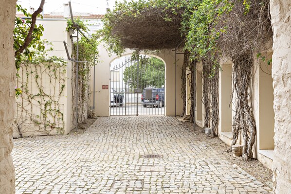 A cobblestone pathway leading to a gated entrance with a wrought iron gate. - Cosy flat, ideal for 4px (Tavira)