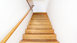 Una scala in legno con corrimano che conduce a una porta bianca.