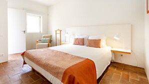 Una camera da letto con un letto grande, un comodino con una lampada, una sedia e una finestra.