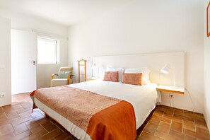 A neatly arranged bedroom with a large bed, bedside tables, a chair, and a window. - Cosy flat, ideal for 4px (Tavira)