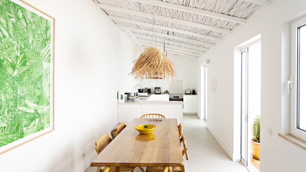 A modern kitchen with white cabinets, a wooden dining table, and a hanging light fixture. - Modern, w/ pool and terrace (Vila Real de Santo António)