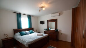 Ein Schlafzimmer mit einem hölzernen Bett, einem Nachttisch, einer Kommode, einem Spiegel und einer Deckenleuchte.