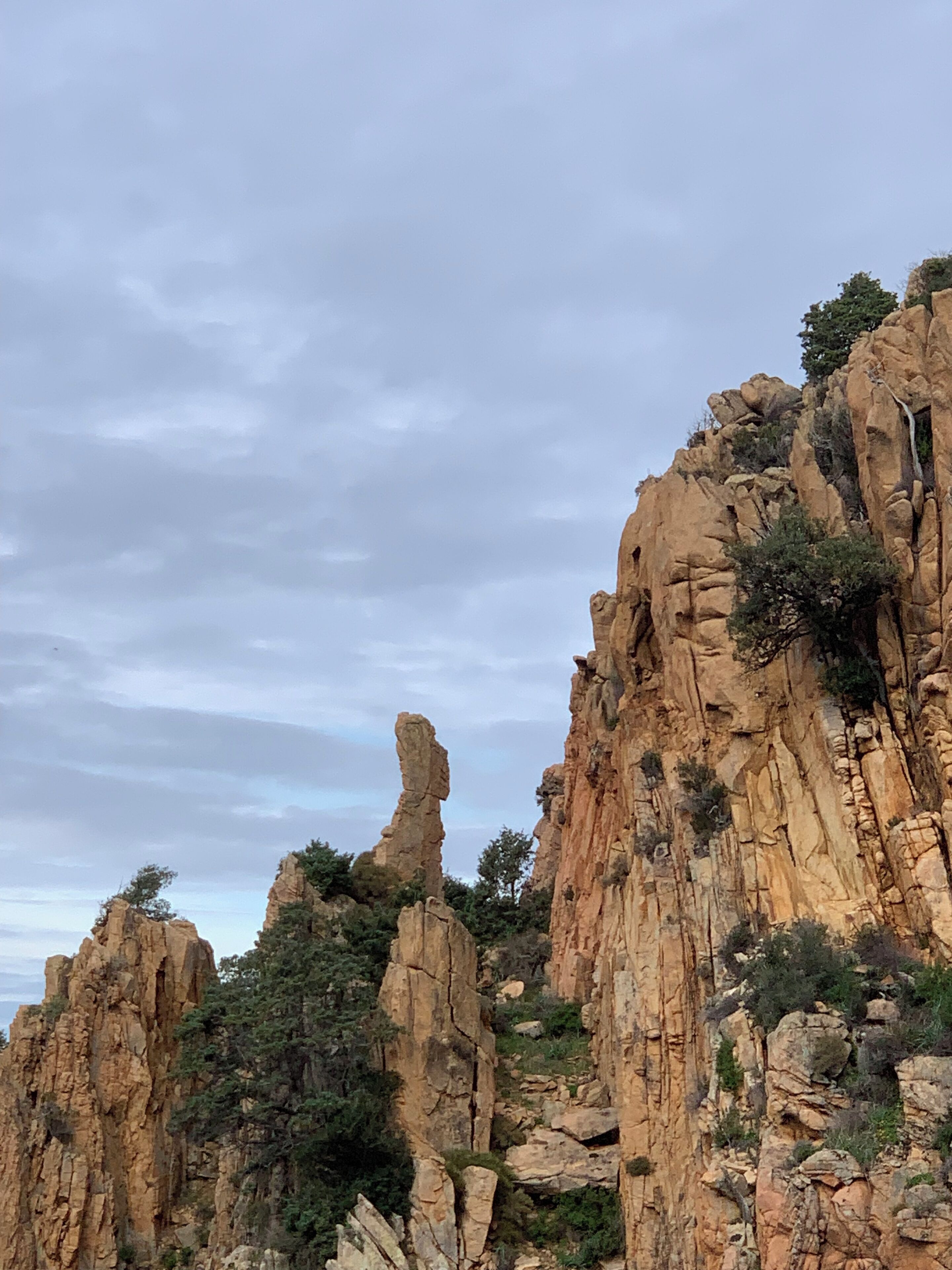 A rugged cliff with prominent rock formations and sparse vegetation.