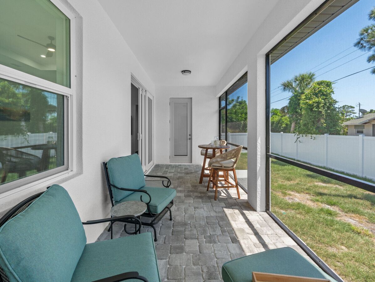 A covered patio with seating, a door, and a view of the outdoors.