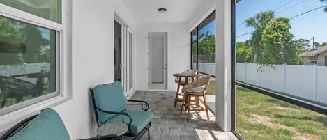 A covered patio with seating, a door, and a view of the outdoors.