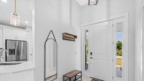 A modern kitchen with a stainless steel refrigerator, a white countertop, and a hanging light fixture. - Sunset Estate near Venice Beach (Venice)