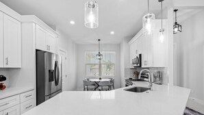 A modern kitchen with white cabinetry, a large island, stainless steel appliances, and pendant lighting. - Sunset Estate near Venice Beach (Venice)