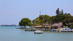 A waterfront area with boats docked, a thatched-roof structure, and a clear sky. - Sunset Estate near Venice Beach (Venice)