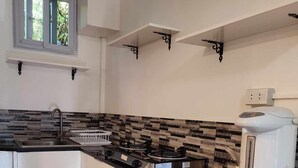 Una cocina moderna con encimera negra, armarios blancos y una ventana sobre el fregadero.
