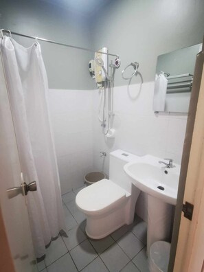 Een kleine badkamer met toilet, wastafel en douche.