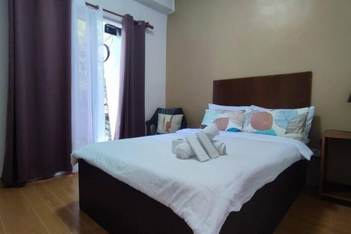 A neatly made bed with white linens and a pillow with a floral pattern.